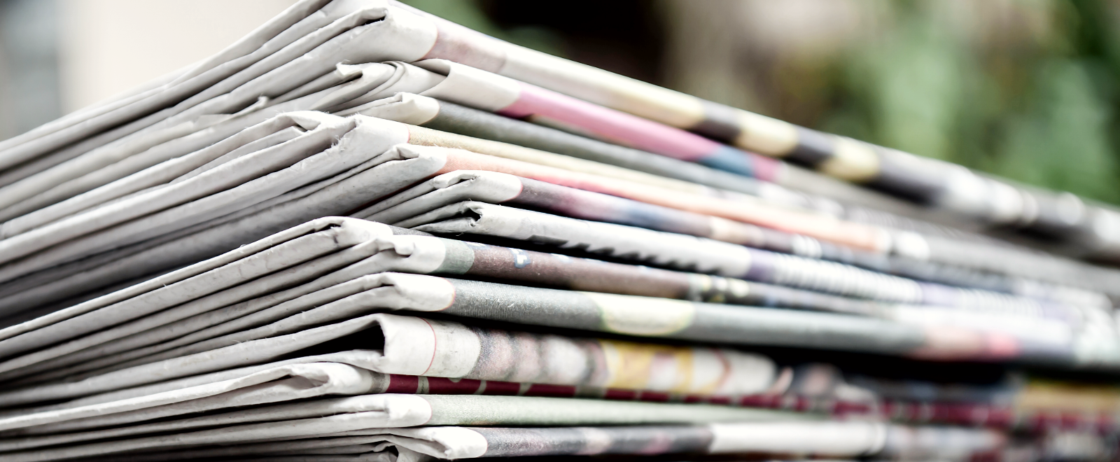 A stack of newspapers sits on an outside porch.
