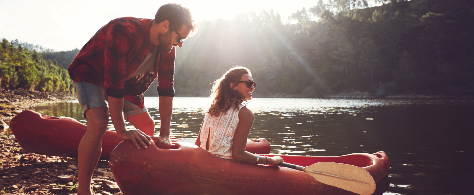 Man and woman prepare to slide kayaks into freshwater inlet.